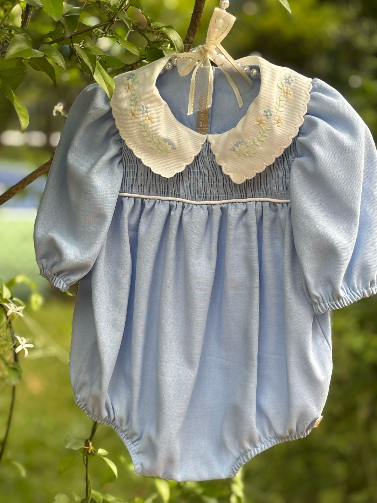 Bombacho Alice amarelo com bordado floral na gola e mangas bufantes, feito em percal 100% algodão, ideal para bebês de 3 a 18 meses.
