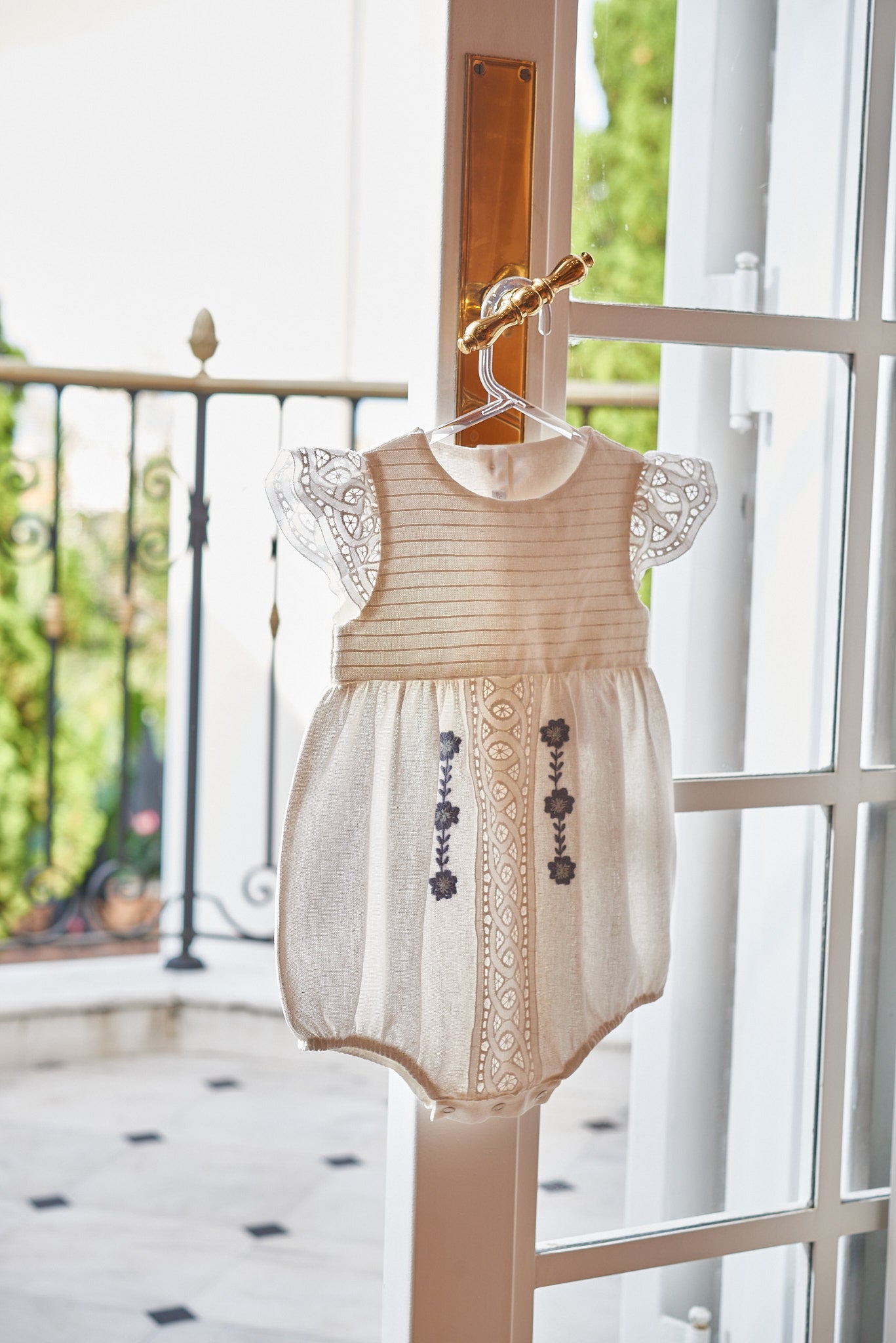 Bombacho Mirela em linho com bordado azul, babados delicados e botões nas costas e entrepernas. Elegância e conforto para bebês de 3 a 18 meses.

