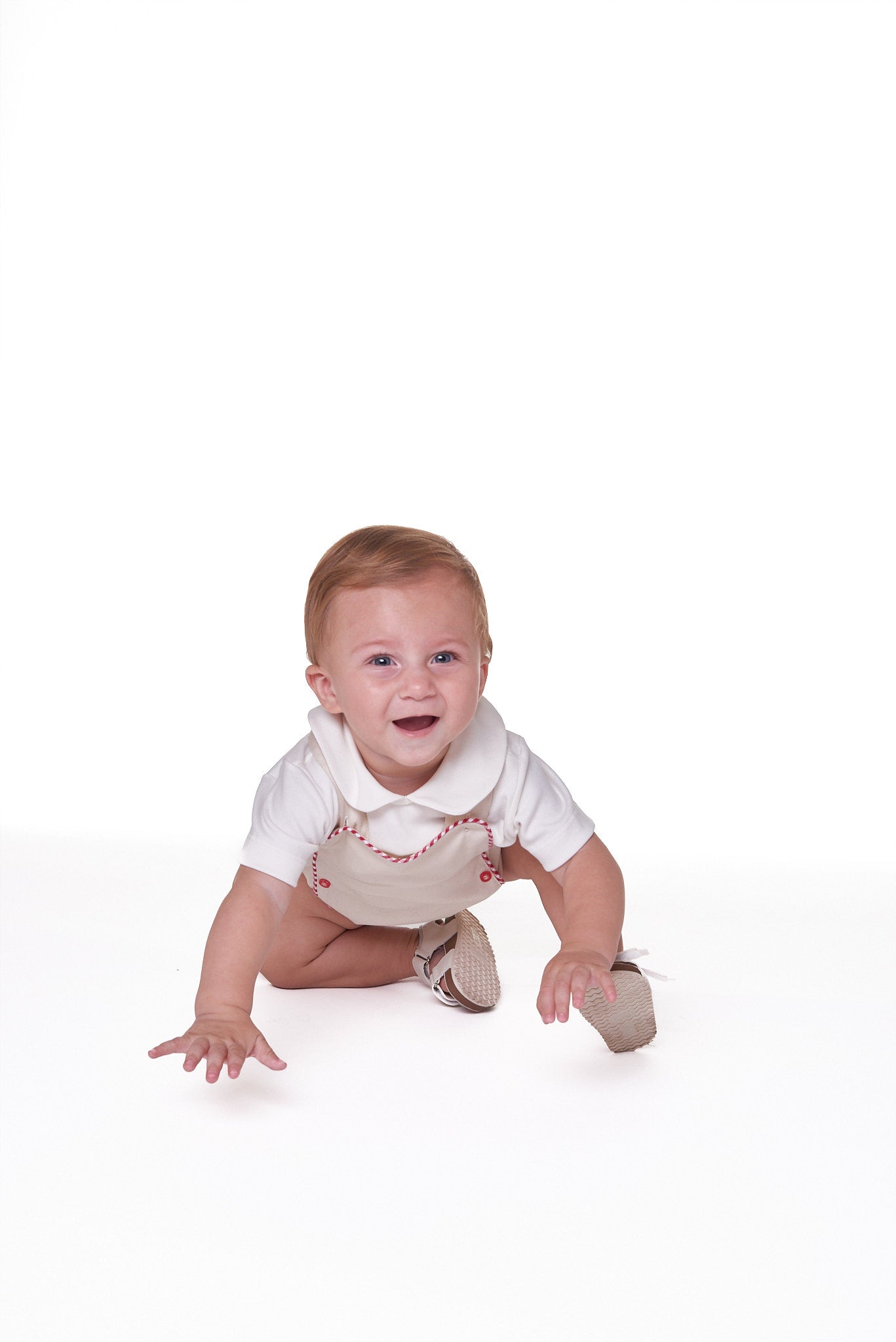 Jardineira Liam em sarja bege com vermelho e azul, edição especial. Clássica, confortável e ideal para bebês de 3 a 18 meses.

