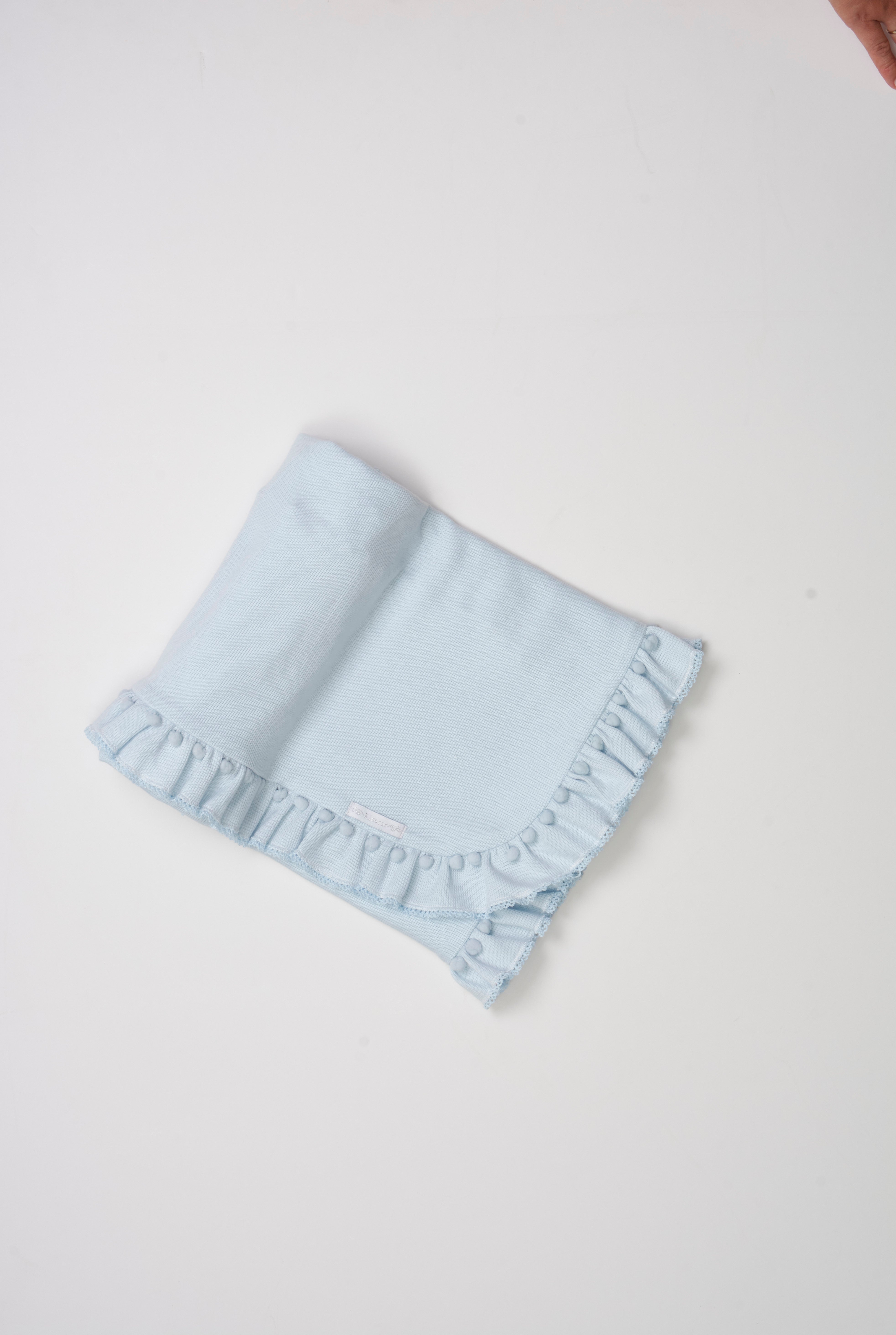 Manta tricotada com babado, mini pompom e picueta – aconchegante e delicada para o bebê.

