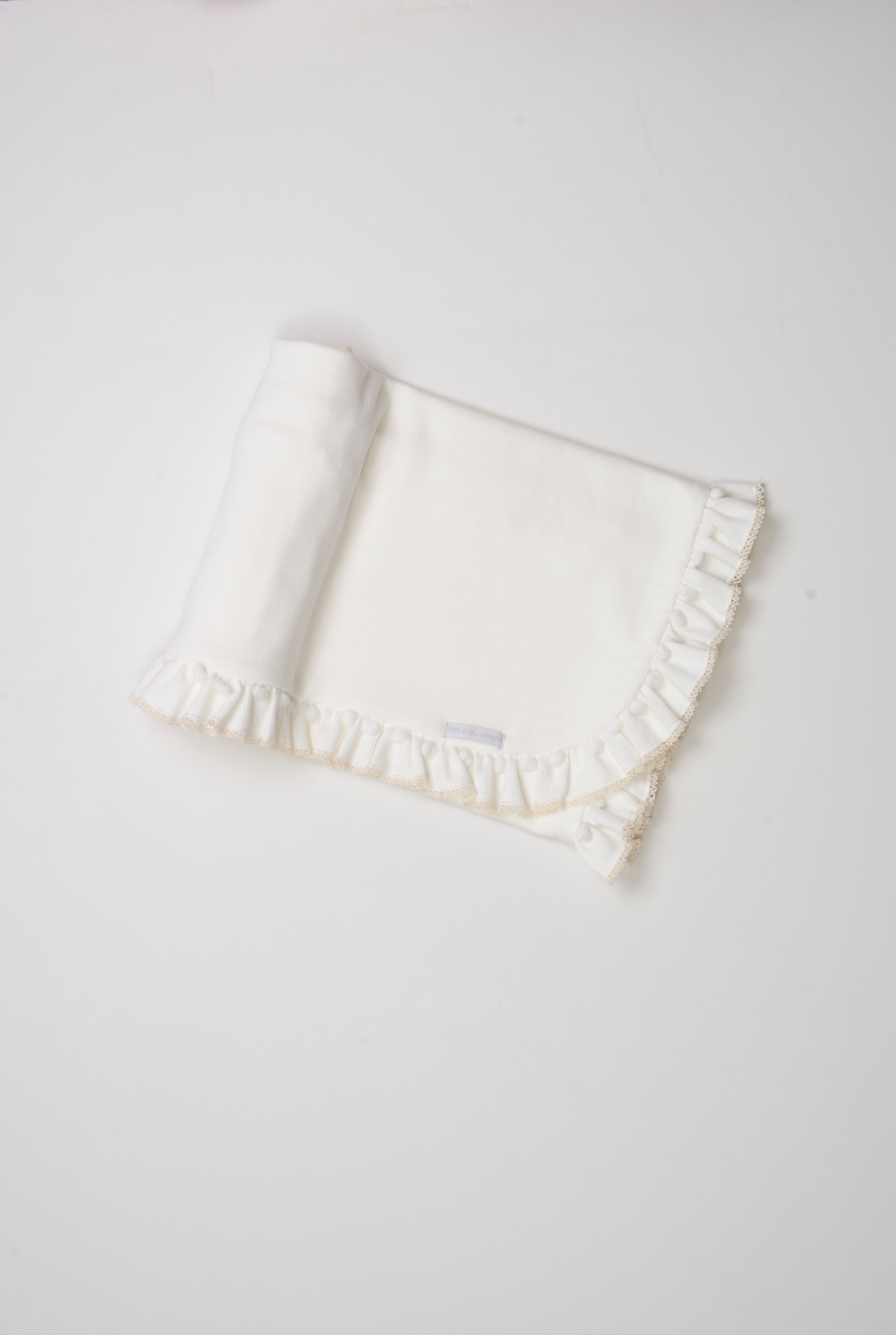 Manta tricotada com babado, mini pompom e picueta – aconchegante e delicada para o bebê.

