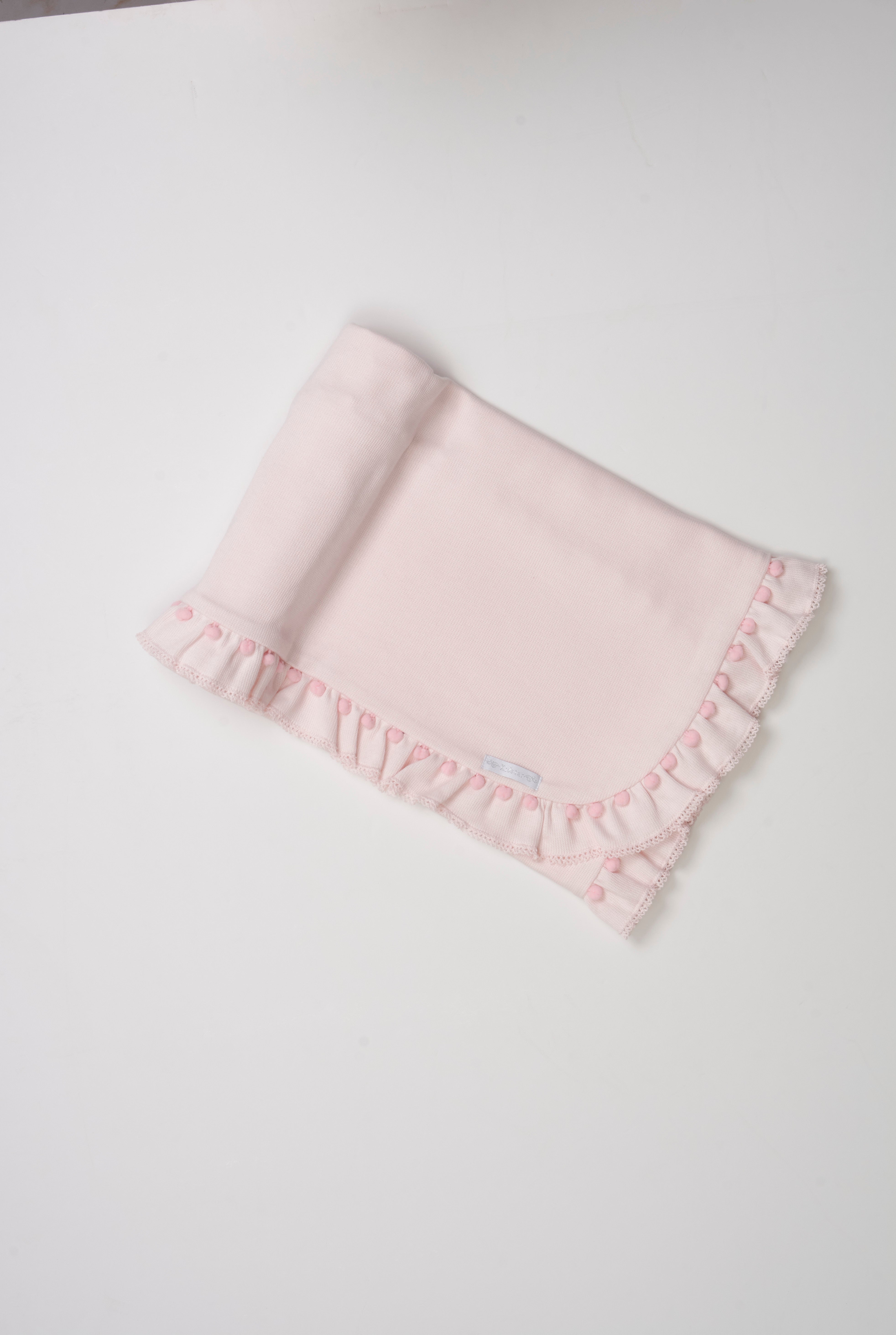 Manta tricotada com babado, mini pompom e picueta – aconchegante e delicada para o bebê.

