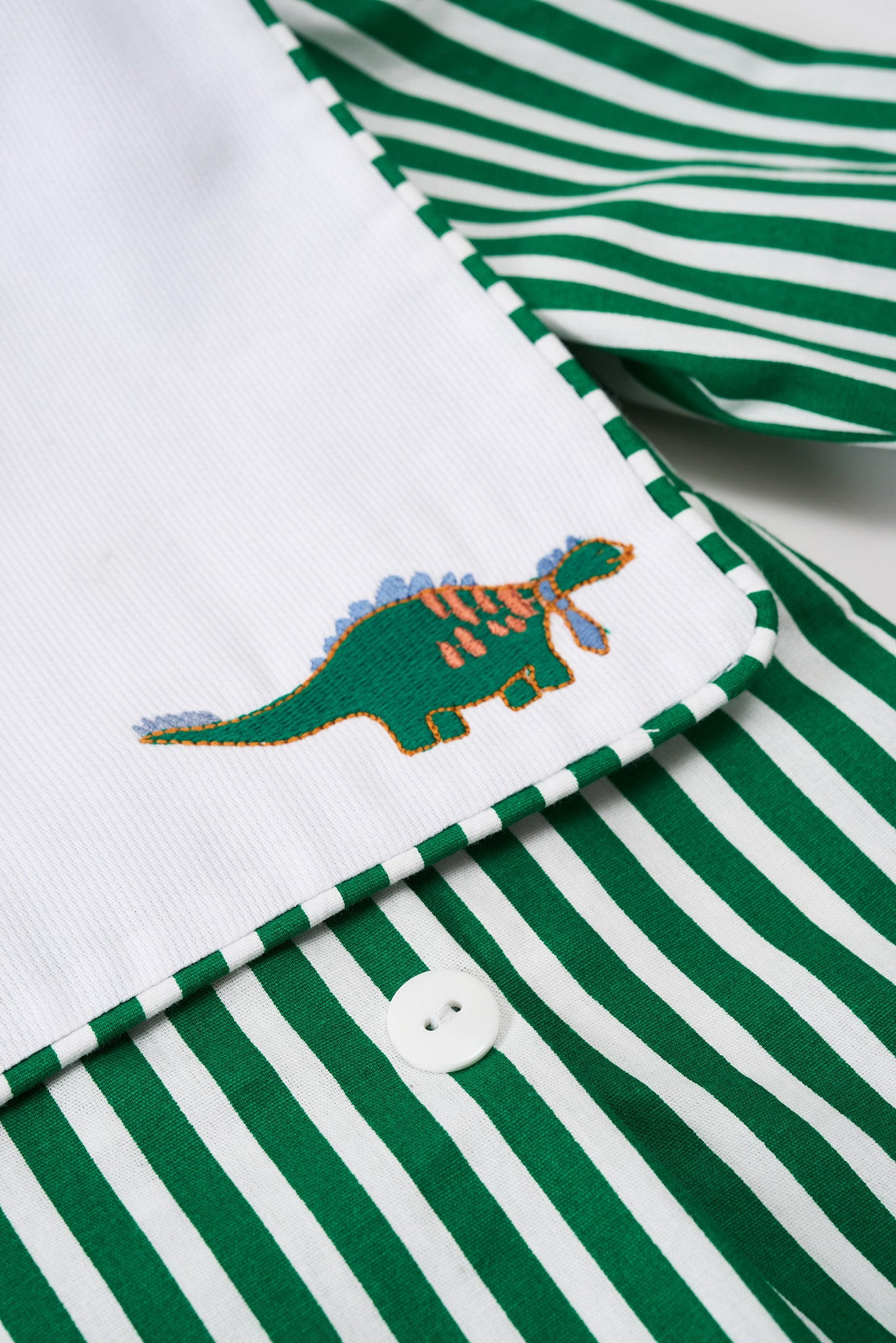 Romper em tricoline com pregas, bordado e botões. Confortável, elegante e fácil de vestir. Para bebês de 3 a 18 meses.
